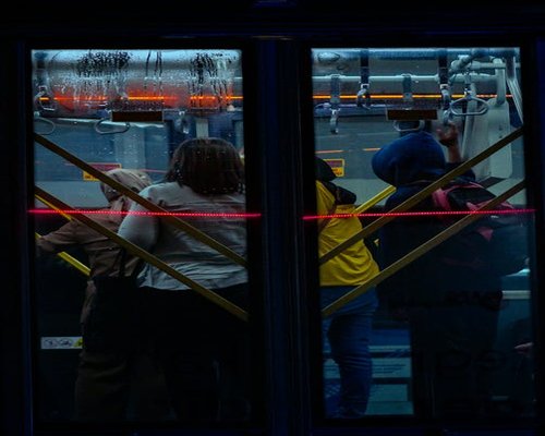 Commuter holding onto the rail in a Jakarta public transport bus, standing comfortably
