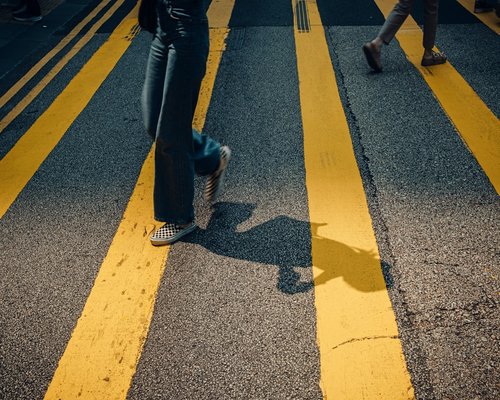 Person wearing comfortable walking shoes walking on a paved city sidewalk